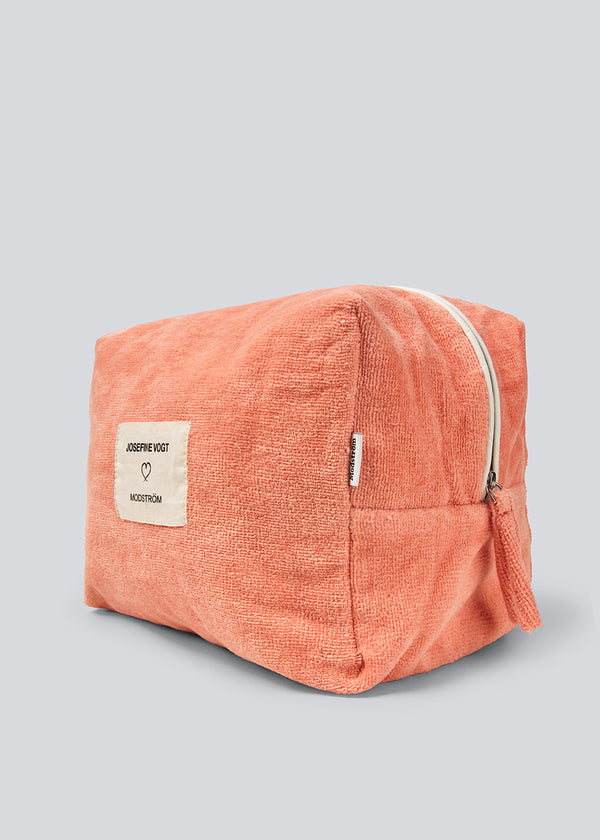 Peach colored toiletry bag with a sewn-on logo. Josefinemd toiletry bag is minimalist and made from organic cotton with a light blue lining and zip closure. Practical and elegant – a must-have for travel or the bathroom.
