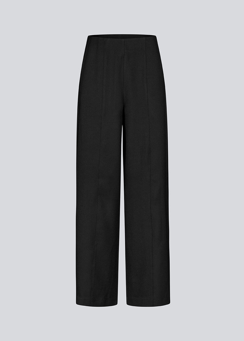 Loose black pants with stitched pintock. KammyMD pants has an invisible zipper, side pockets and an elastic waist.