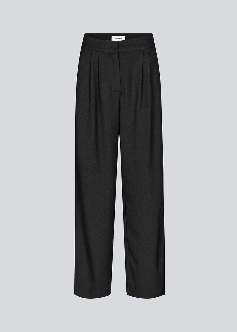 Suit pants in a structured material wide legs and pleats at the top. KarterMD pants in Black has a medium-high waist, zipper, side pockets and paspoil pockets in the back.