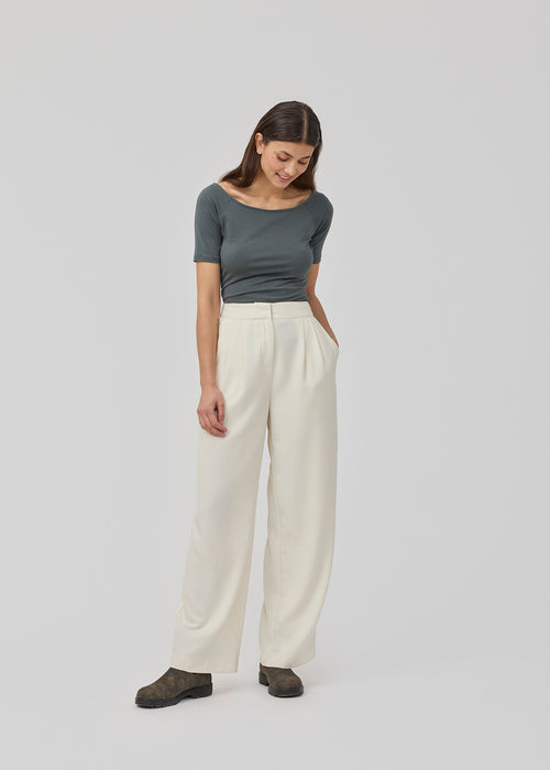 Suit pants in a structured material wide legs and pleats at the top. KarterMD pants in SOft White has a medium-high waist, zipper, side pockets and paspoil pockets in the back.