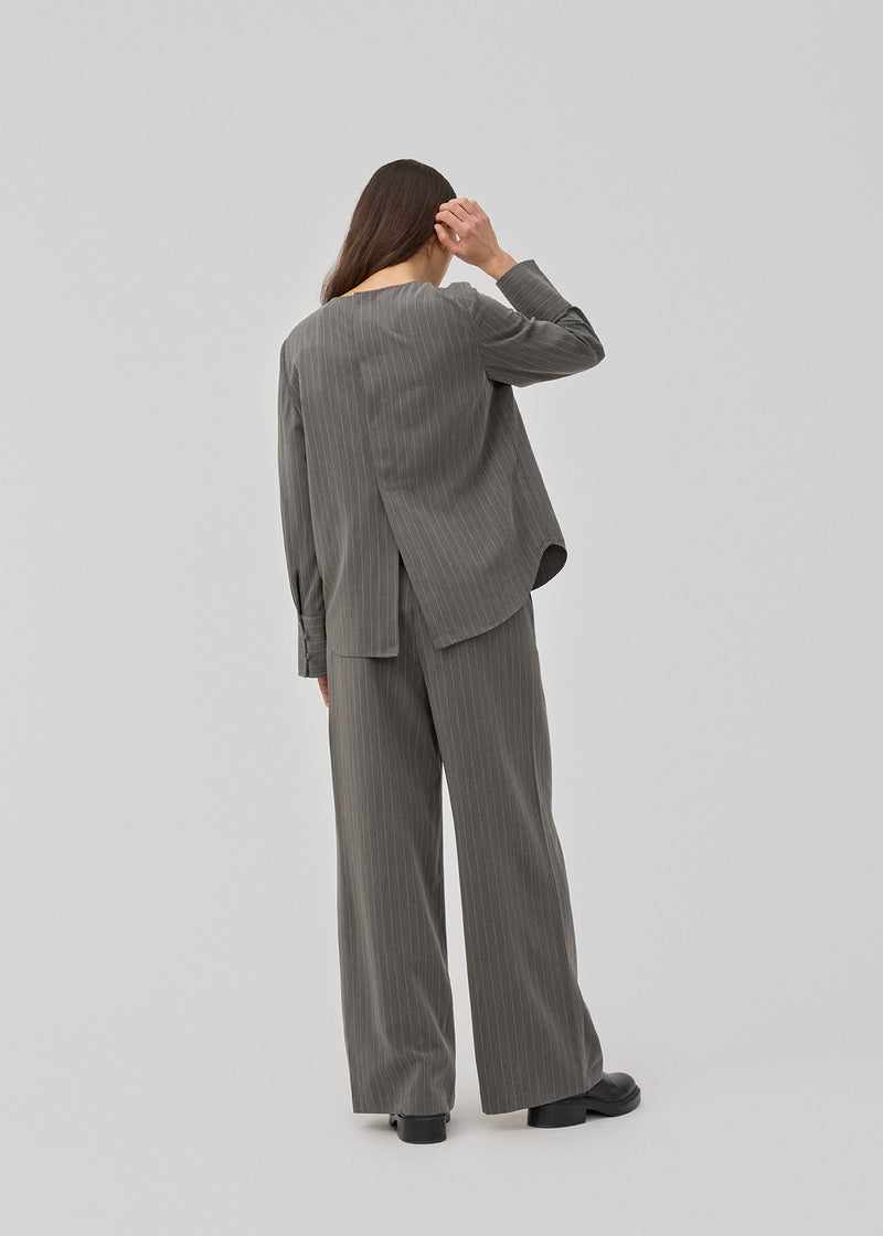 Pants in grey pinstripe with wide legs. KemmaMD pants has side pockets, a medium high waist, zipper and paspoil back pockets.