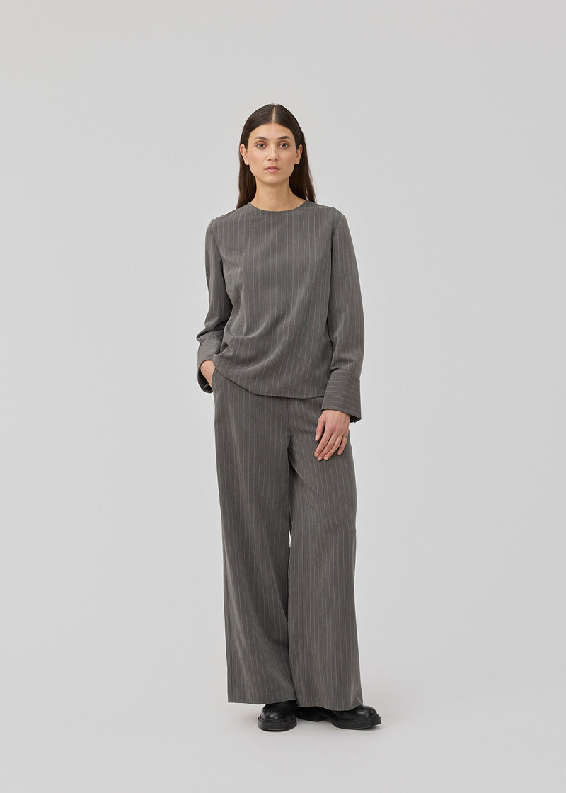 Pants in grey pinstripe with wide legs. KemmaMD pants has side pockets, a medium high waist, zipper and paspoil back pockets.
