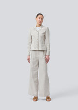 Short fitted blazer in beige melange in a structured material. KieraMD jacket has two pockets at the front and a slit at the sleeves with button closure.

