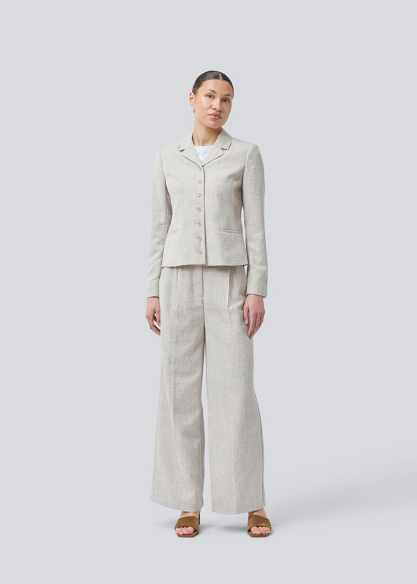Short fitted blazer in beige melange in a structured material. KieraMD jacket has two pockets at the front and a slit at the sleeves with button closure.

