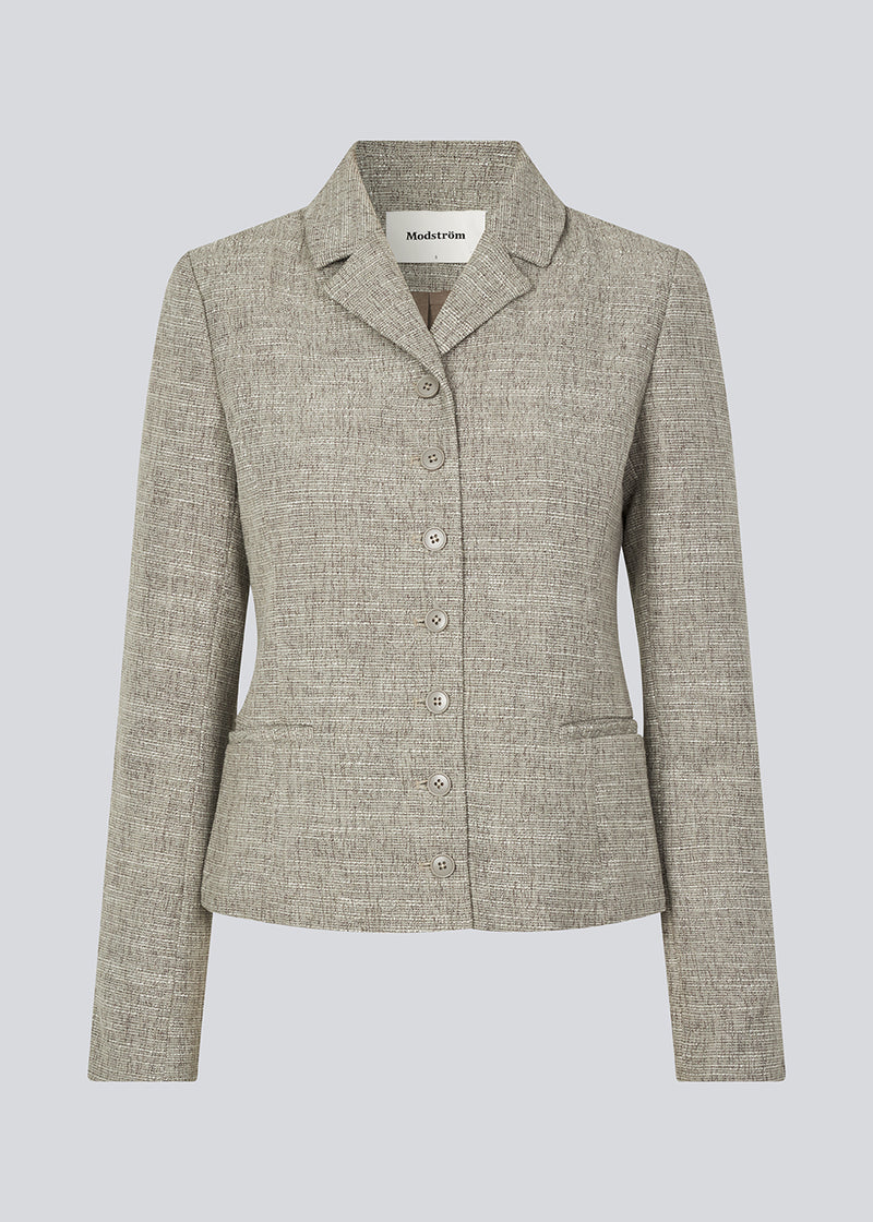 Short fitted blazer in a structured material. KieraMD jacket has two pockets at the front and a slit at the sleeves with button closure.