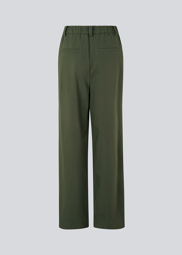 Suit pants in a dark green with wide legs and pleats at the top. KimanaMD pants has a medium-high waist, zipper, side pockets and paspoil pockets in the back.