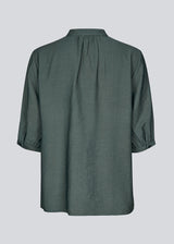 Loose shirt in dark green with short sleeves and a ruffel detail. KirisMD top has a button closure in front and puff sleeves.