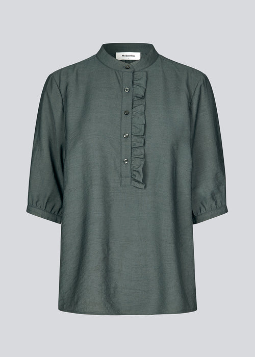 Loose shirt in dark green with short sleeves and a ruffel detail. KirisMD top has a button closure in front and puff sleeves.