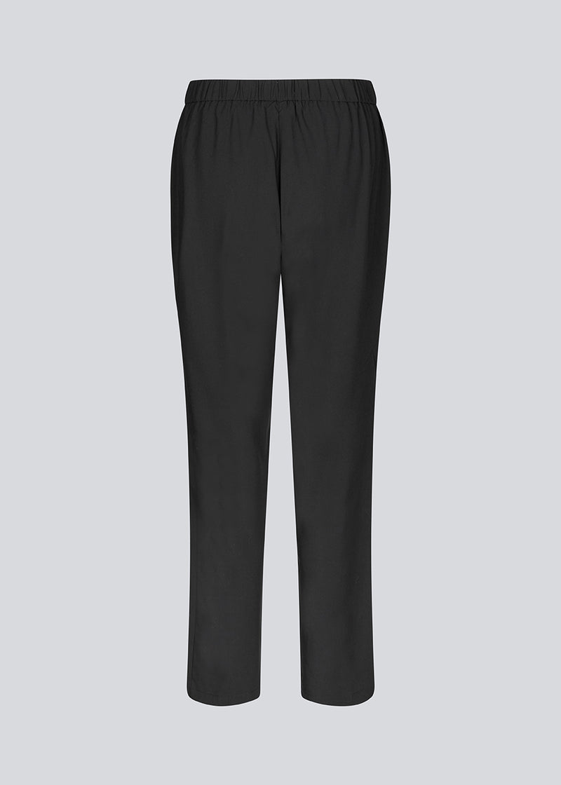 Loose black pants with a high waist. KollinMD pants have a fly, side pockets and elastic in the waist.