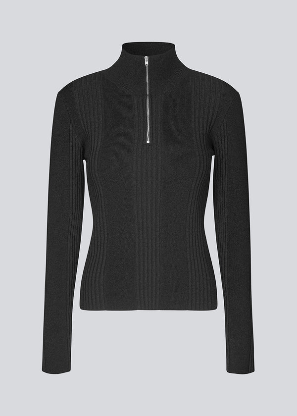 Fitted knit with a high neck. KrissaMD zip t-neck in Black is in rib knit and has a zipper in front.