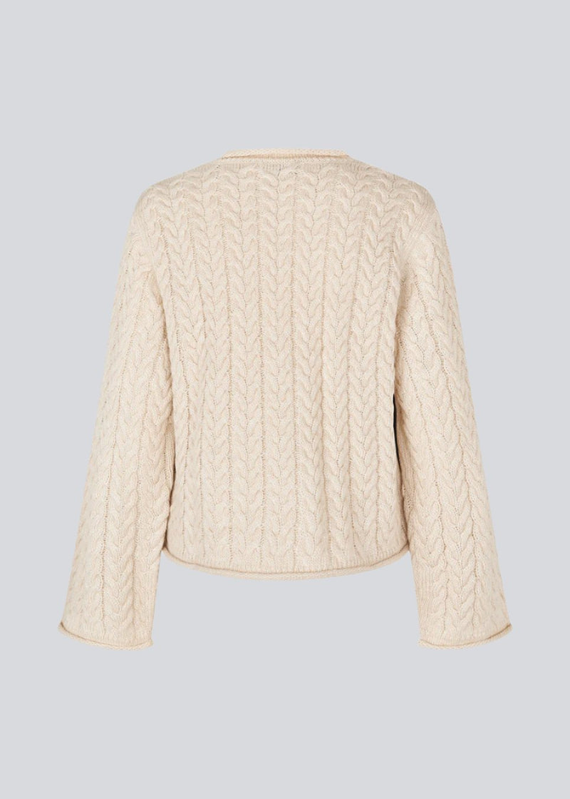 Loose creme knit with wide sleeves in cable knit. KurtisMD o-neck has a round neckline and rolled edges.