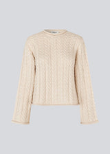 Loose creme knit with wide sleeves in cable knit. KurtisMD o-neck has a round neckline and rolled edges.