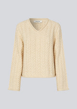 Loose wool knit in creme color with wide sleeves. KurtisMD v-neck has a v-neck and rolled edges.