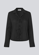 Classic shirt with tieband closure in an elastic and slightly see-through material. LaceyMD shirt has wide sleeves with slits and tree tiebands in front.
