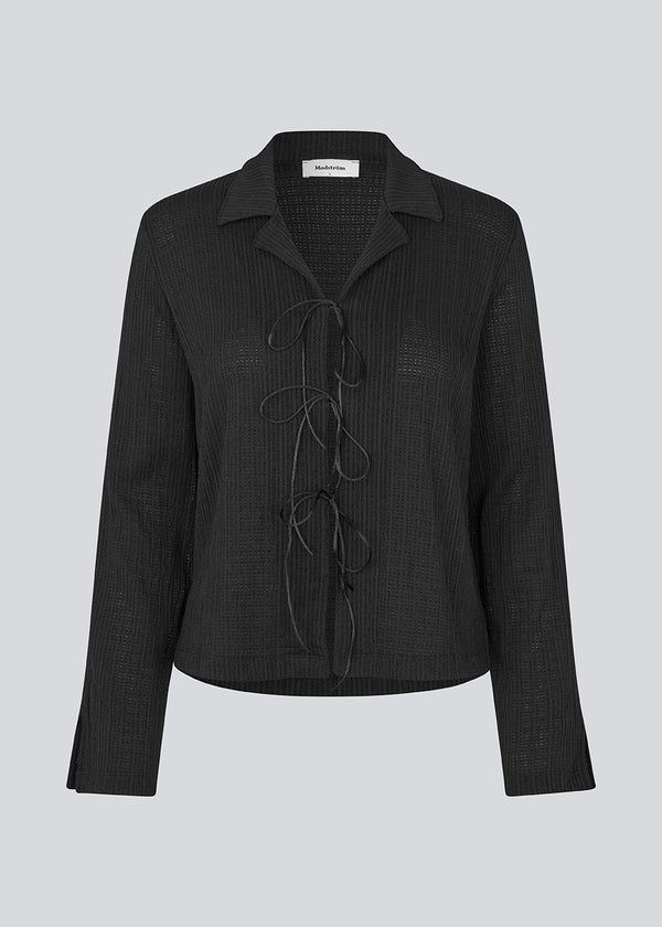 Classic shirt with tieband closure in an elastic and slightly see-through material. LaceyMD shirt has wide sleeves with slits and tree tiebands in front.