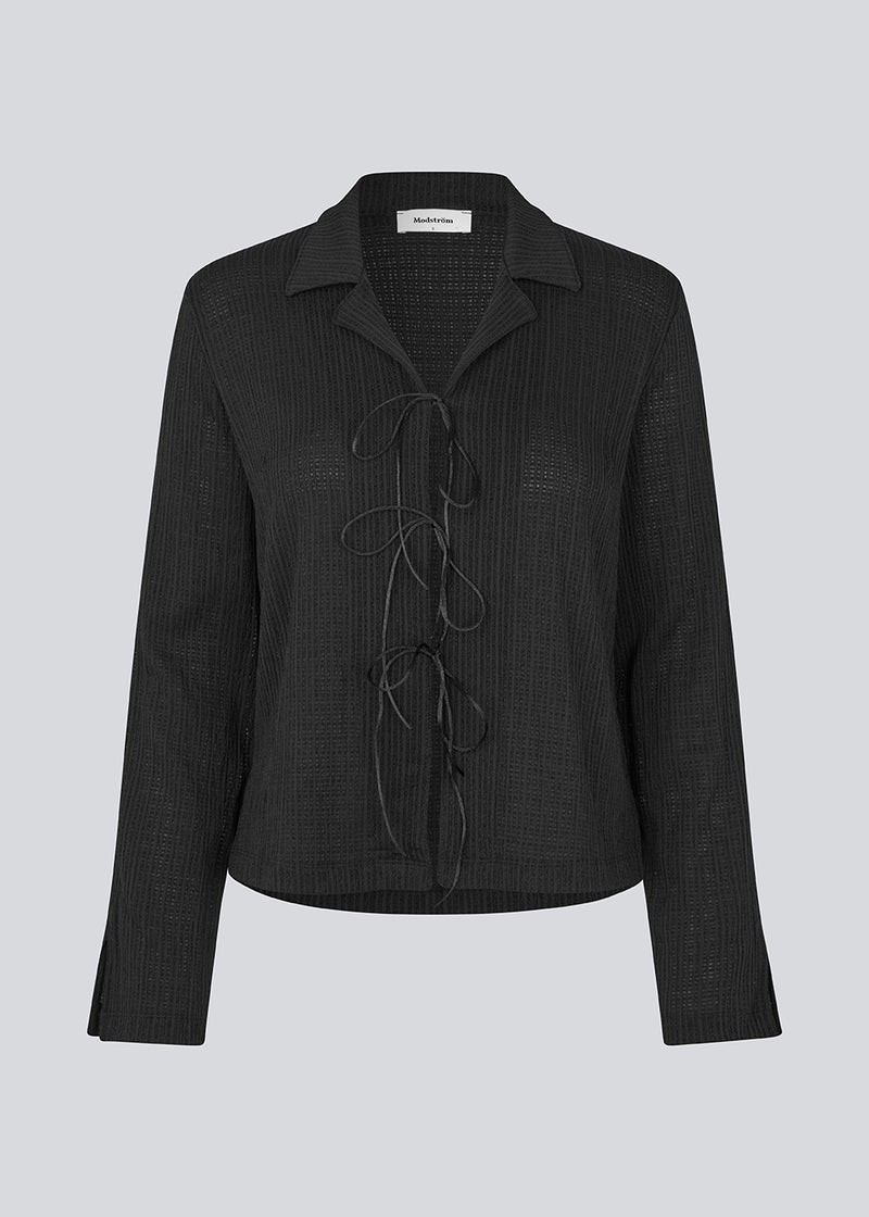 Classic shirt with tieband closure in an elastic and slightly see-through material. LaceyMD shirt has wide sleeves with slits and tree tiebands in front.