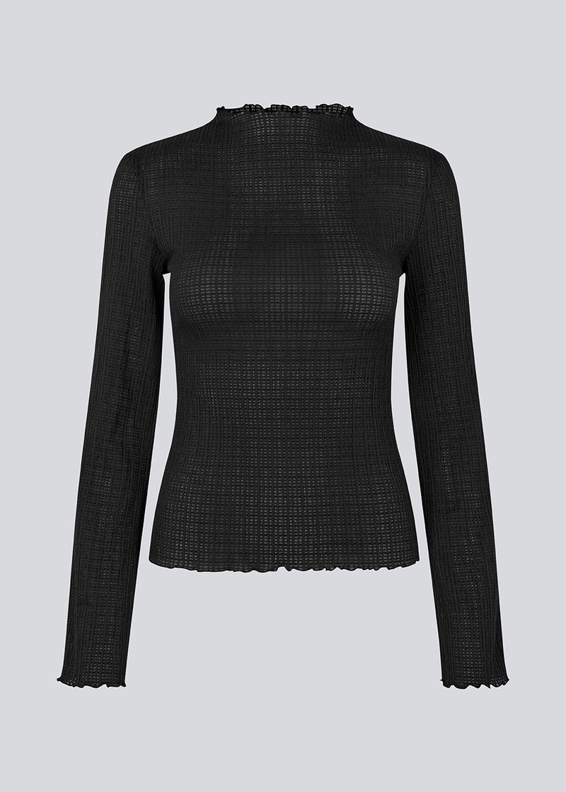 Longsleeved black top in an elastic and slighly see-through material. LaceyMD is fitted and has a high neck.