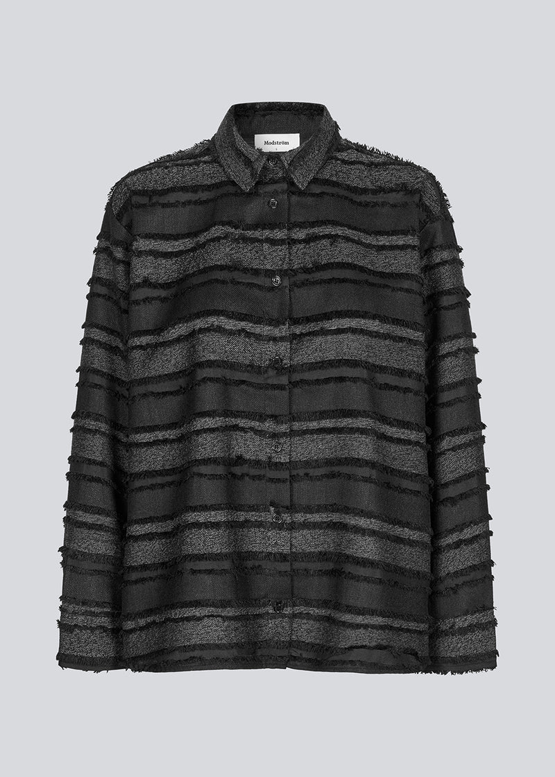 Black shirt in fringed polyester. LiljaMD shirt has a cuf with buttonclusre, a classic shirtcollar and a button closure in front.