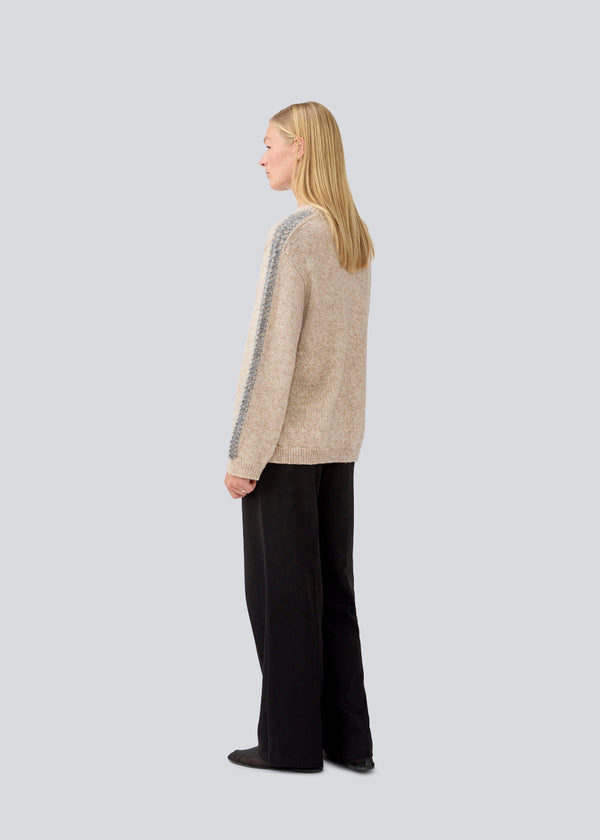 Soft beige knit with grey stitching details on the sleeves. LineMD o-neck is made in plain jersey knit, and has a round neck, loose fit, and slits in the sides. The model is 177 cm and wears a size S/36.