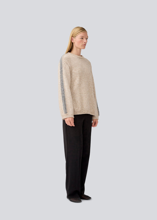 Soft beige knit with grey stitching details on the sleeves. LineMD o-neck is made in plain jersey knit, and has a round neck, loose fit, and slits in the sides. The model is 177 cm and wears a size S/36.