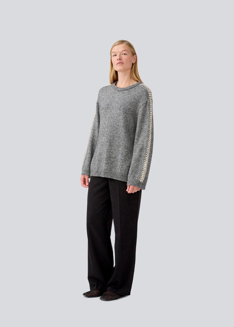Soft knit in dark grey with beige stitching details on the sleeves. LineMD o-neck is made in plain jersey knit, has a round neck and loose fit. The model is 177 cm and wears a size S/36.
