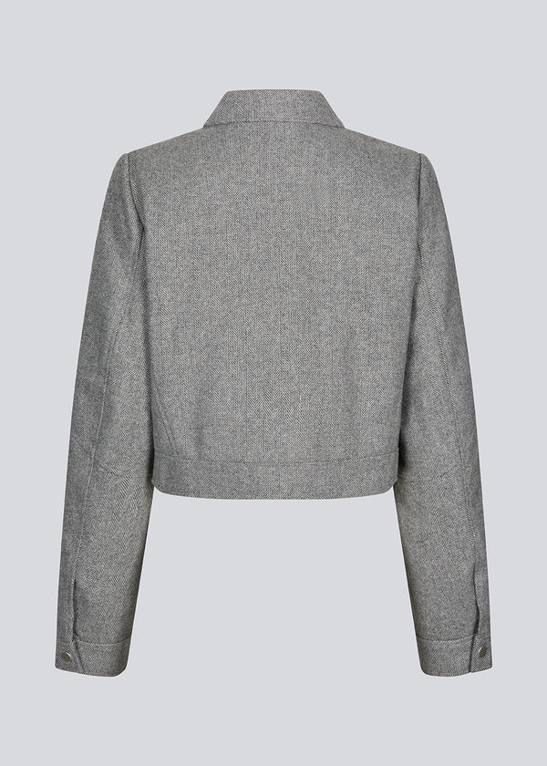 Cropped grey jacket in 80% wool. LissieMD jacket has a classic collar, manchet with button closure and a zipper in front. The model is 177 cm and wears a size S/36.