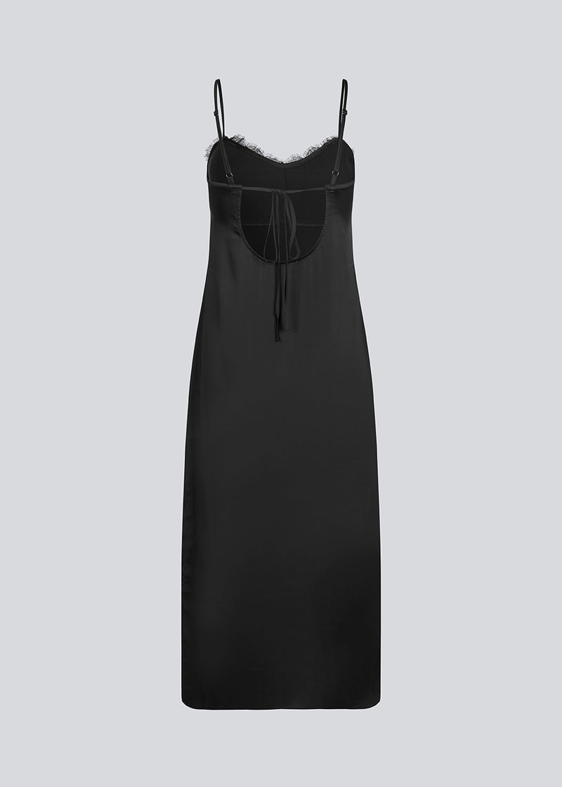 Long black dress in satin with a lace detail on the chest and an open back. LivMD dress is fitted, has thin adjustable straps and a slit in the side.