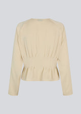 Fitted creme-colored top with boxpleats in satin. LivMD shirt has a button closure in front and loose sleeves.