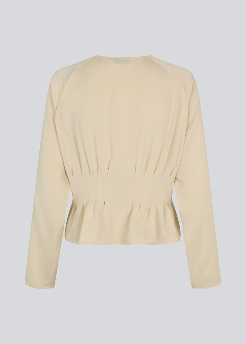 Fitted creme-colored top with boxpleats in satin. LivMD shirt has a button closure in front and loose sleeves.