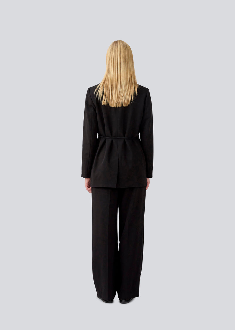 Classic black blazer with an oversize fit and a tieband at the waist. LykkeMD blazer has a satin detail on the collar and a slit in the back. The model is 177 cm and wears a size S/36.