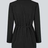 Classic black blazer with an oversize fit and a tieband at the waist. LykkeMD blazer has a satin detail on the collar and a slit in the back. The model is 177 cm and wears a size S/36.