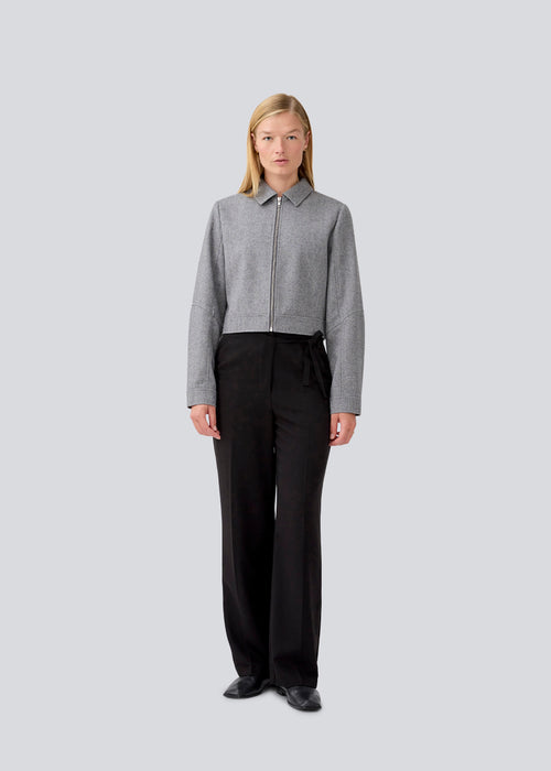 Black suitpants with a tieband at the waist. LykkeMD pants has a zipper, side pockets and paspoil back pockets. The model is 177 cm and wears a size S/36.