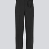 Black suitpants with a tieband at the waist. LykkeMD pants has a zipper, side pockets and paspoil back pockets. The model is 177 cm and wears a size S/36.