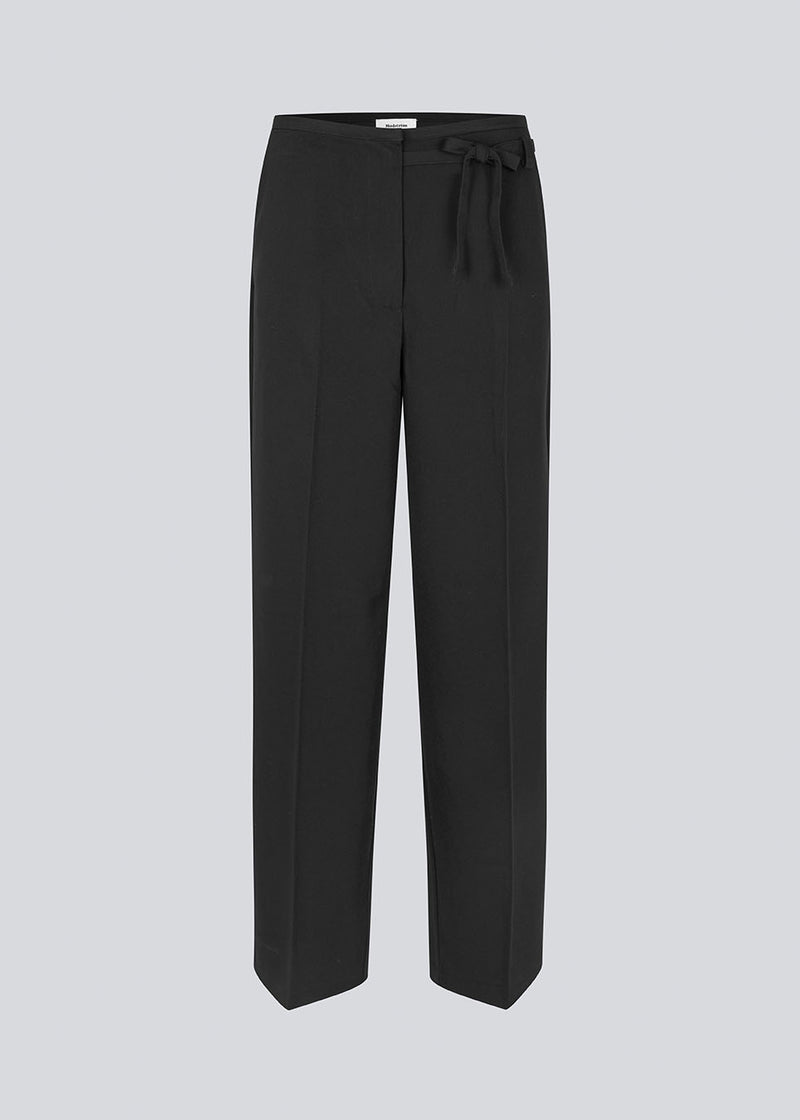 Black suitpants with a tieband at the waist. LykkeMD pants has a zipper, side pockets and paspoil back pockets. The model is 177 cm and wears a size S/36.