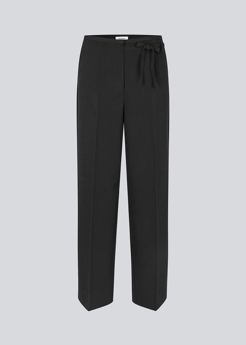 Black suitpants with a tieband at the waist. LykkeMD pants has a zipper, side pockets and paspoil back pockets. The model is 177 cm and wears a size S/36.