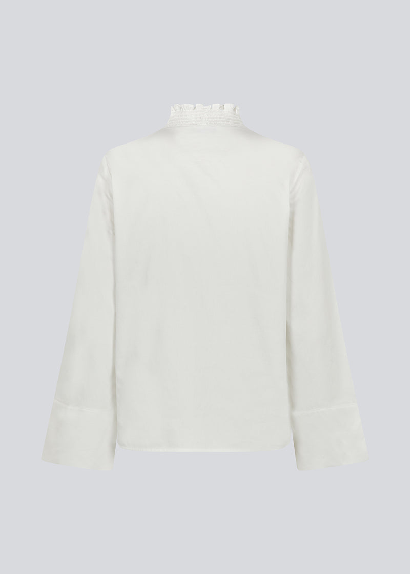 Lose white shirt with v-neck with a smock detail. LylaMD shirt has long wide sleeves with a slit and a buttonclosure in front.