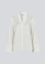 Lose white shirt with v-neck with a smock detail. LylaMD shirt has long wide sleeves with a slit and a buttonclosure in front.