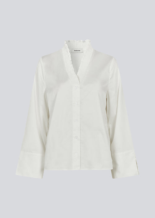 Lose white shirt with v-neck with a smock detail. LylaMD shirt has long wide sleeves with a slit and a buttonclosure in front.