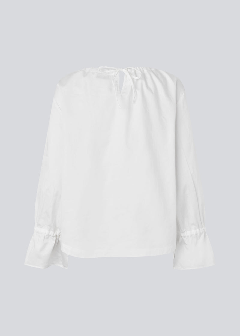 Loose white top with lang sleeves with tiebands. LylaMD top has a round neck with a tieband.