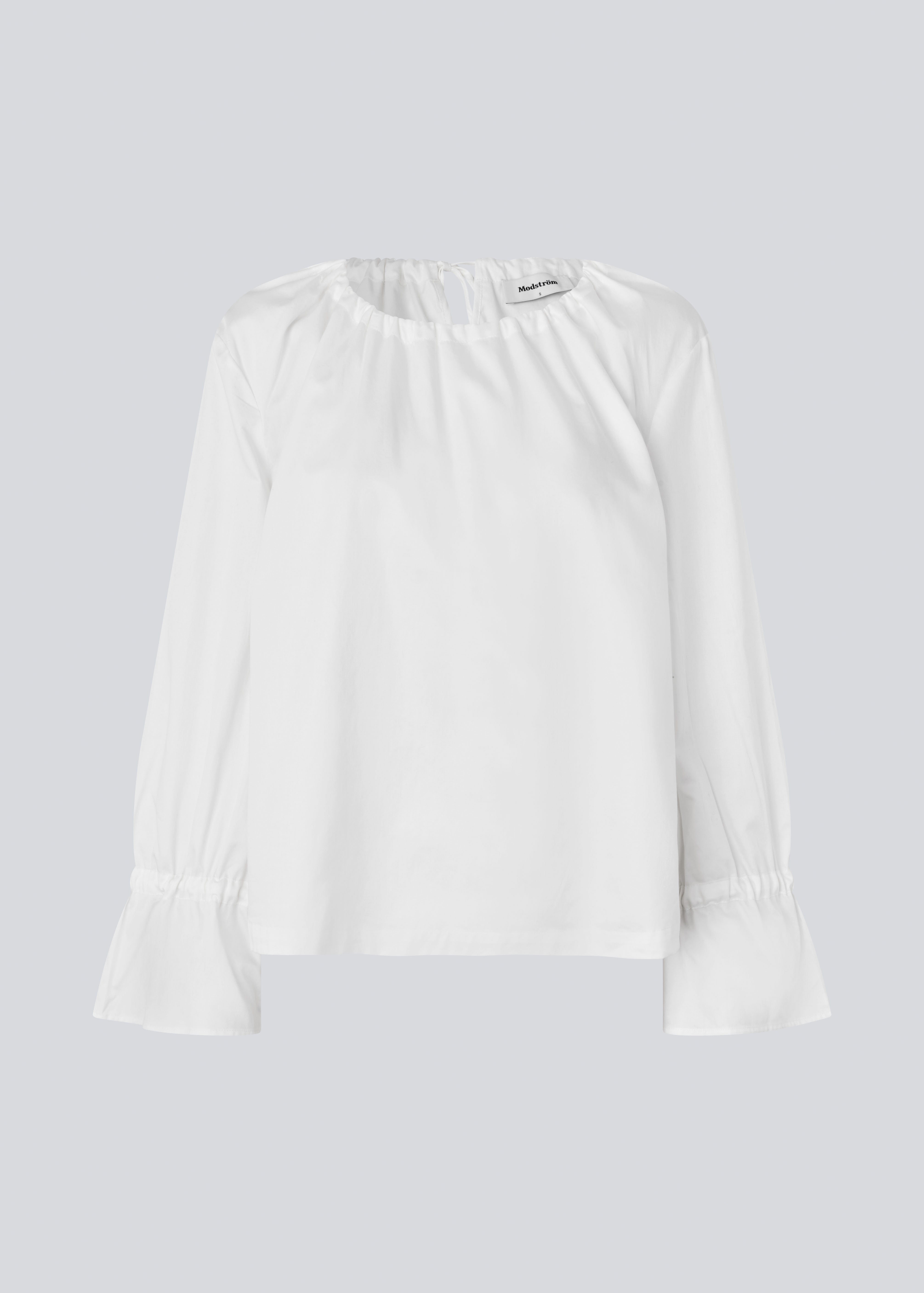 Loose white top with lang sleeves with tiebands. LylaMD top has a round neck with a tieband.