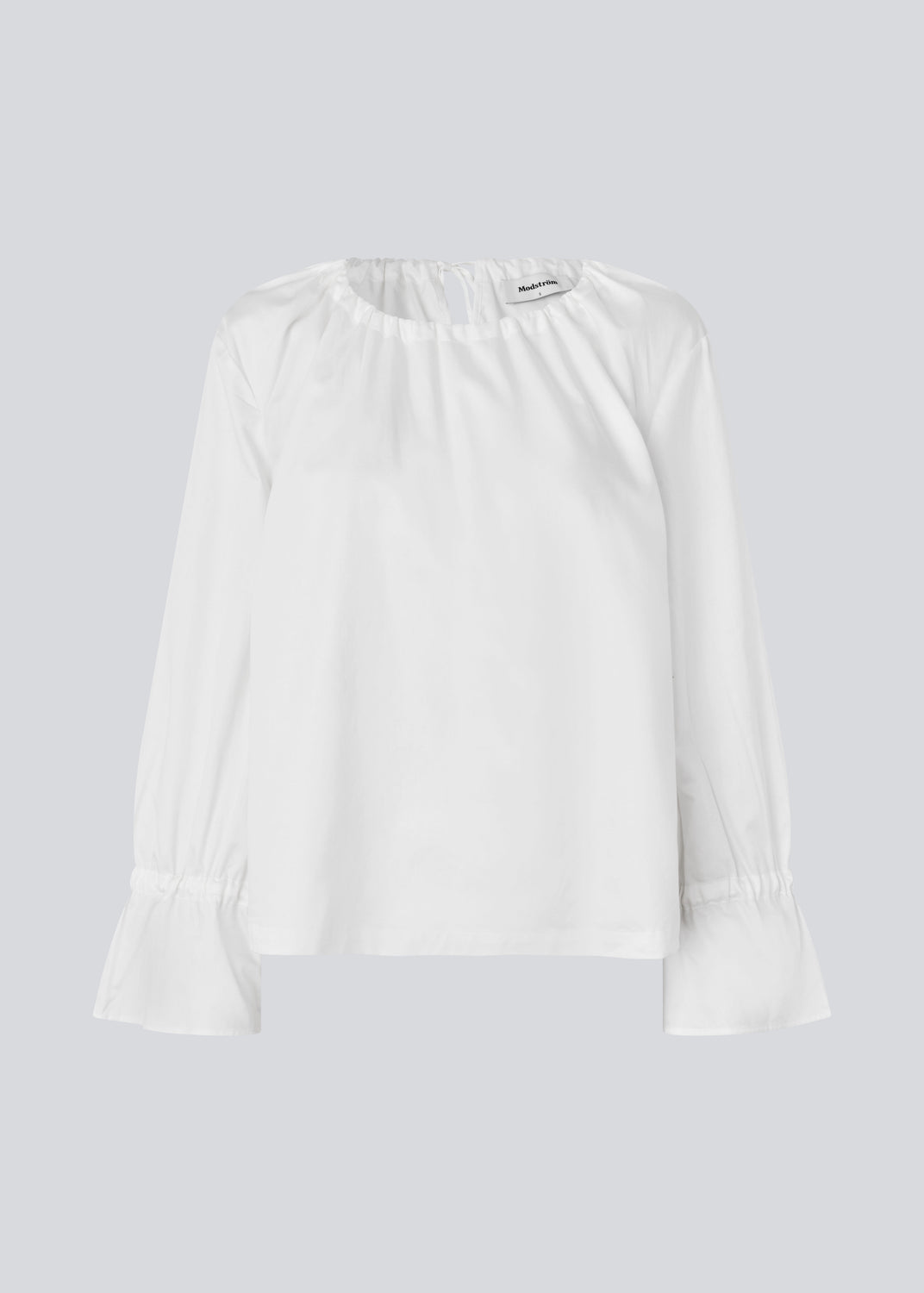 Loose white top with lang sleeves with tiebands. LylaMD top has a round neck with a tieband.