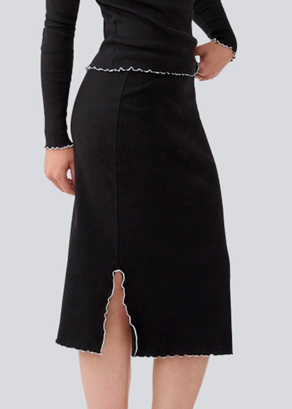 Midi skirt in black with white edges in jersey. MagdaloneMD skirt has slits in the sideseams and babylock edges with an elastic in the waist. The model is 177 cm and wears a size S/36.