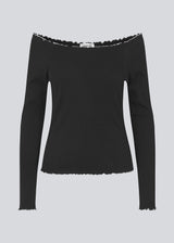 Off-shoulder long sleeve top in black with white edges . MagdaloneMD LS top is fitted and has babylock edges. The model is 177 cm and wears a size S/36.