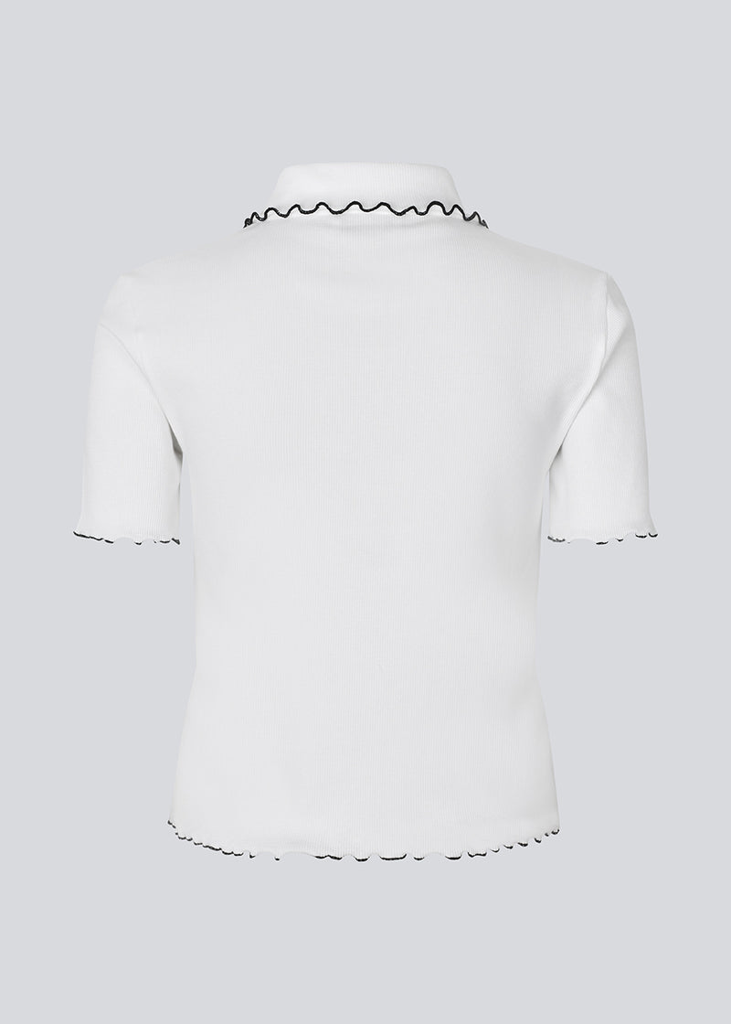 Fitted polo t-shirt in white with black edges in jersey. MagdaloneMD polo has short sleeves and babylock edges. The model is 177 cm and wears a size S/36