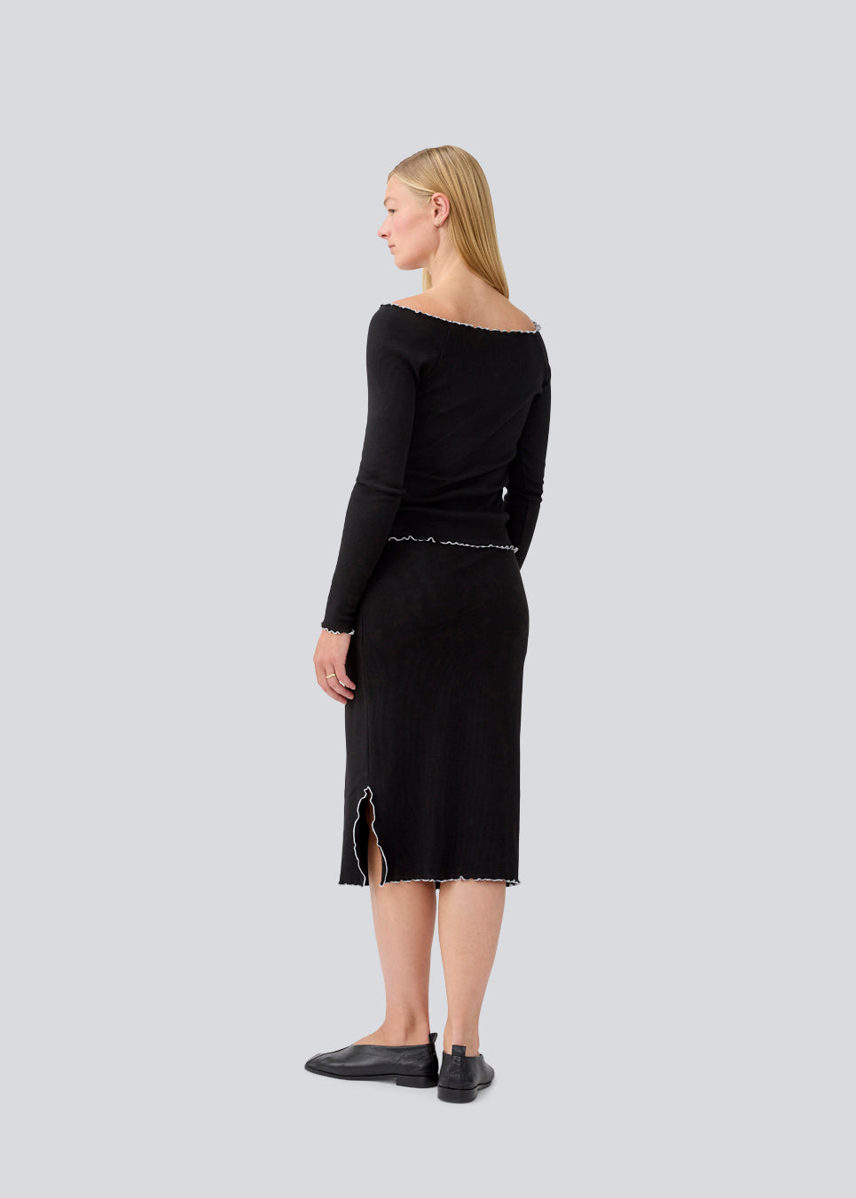 Midi skirt in black with white edges in jersey. MagdaloneMD skirt has slits in the sideseams and babylock edges with an elastic in the waist. The model is 177 cm and wears a size S/36.