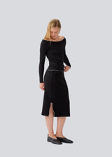 Midi skirt in black with white edges in jersey. MagdaloneMD skirt has slits in the sideseams and babylock edges with an elastic in the waist. The model is 177 cm and wears a size S/36.
