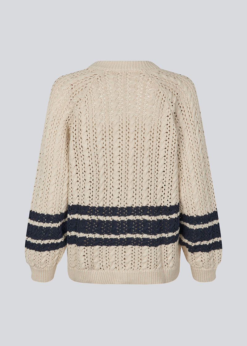 Loose knitted cardigan in beige with navy blue stripes in the button in cable knit. MetteMD cardigan is slightly see-through and has loose sleeves and a button closure. The models are 177 cm and wear a size S/36.&nbsp;
