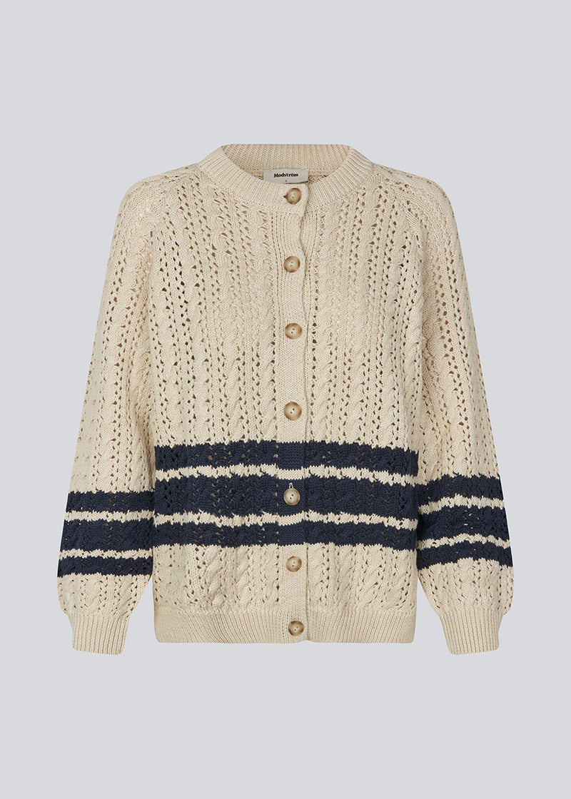 Loose knitted cardigan in beige with navy blue stripes in the button in cable knit. MetteMD cardigan is slightly see-through and has loose sleeves and a button closure. The models are 177 cm and wear a size S/36.&nbsp;
