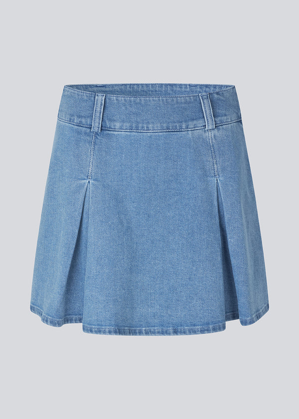 Short skirt with inverted box pleats in denim. MikaMD skirt has a high waist and a zipper in the sideseam. The model is 177 cm and wears a size S/36.