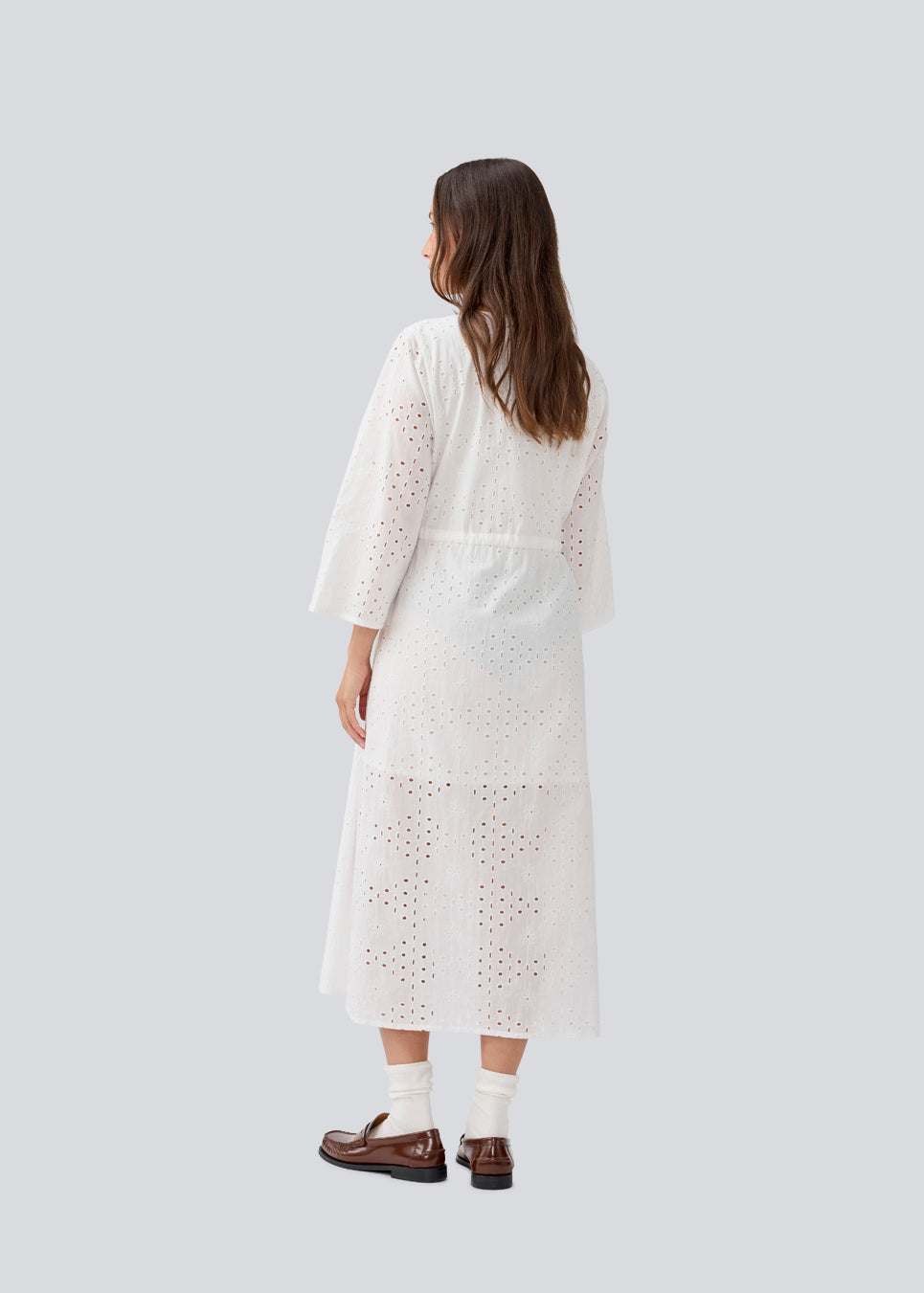 Maxi dress in broderie anglaise. MisoMD dress has a loose fit, v-neck and a tieband at the waist. 